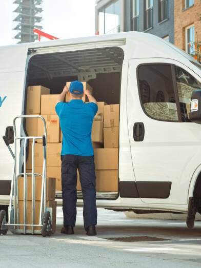 Delivery Man Uses Hand Truck Trolley Full of Cardboard Boxes
