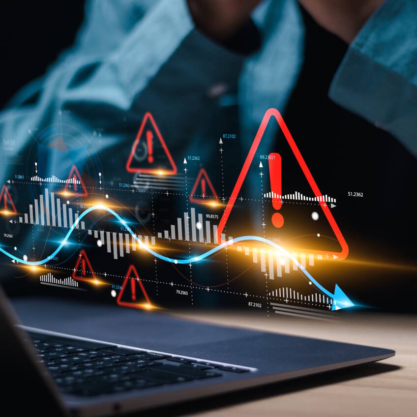 A person using a laptop with data projected along with multiple red warning signs indicating an event requires attention